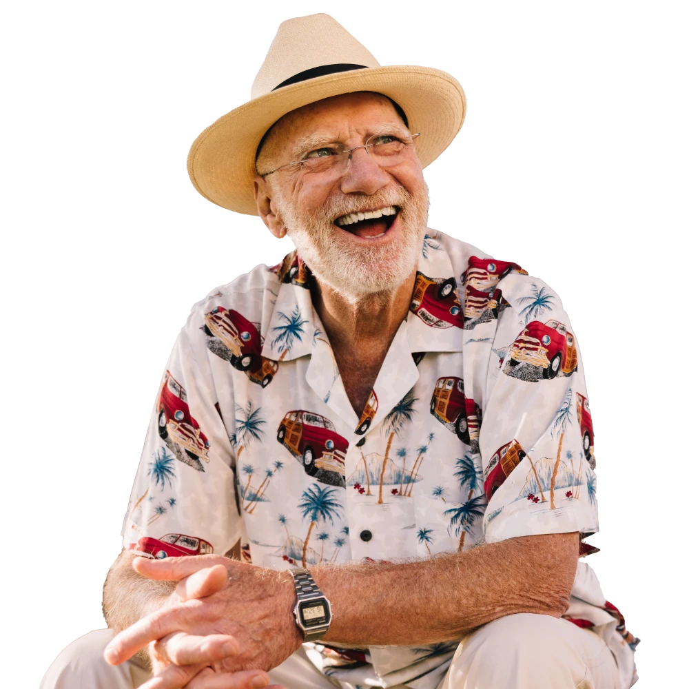Happy older man wearing a straw hat and a colorful shirt, laughing outdoors