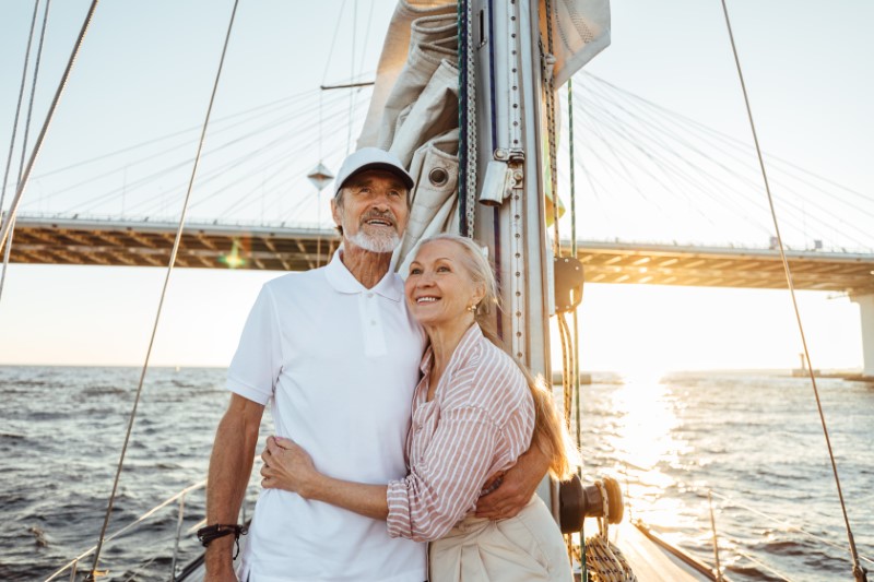 Happy couple on a sailboat looking out into the water